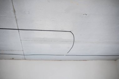 Siyah elektrik kabloları bir odadaki düz bir tavan boyunca görünür..