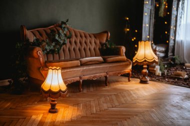 Eski bir oturma odasında soluk bir kanepe, eşsiz lambalar ve yumuşak ışıklandırma bulunur..