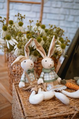 Two cute toy rabbits beside bright flowers create a charming indoor vibe. clipart