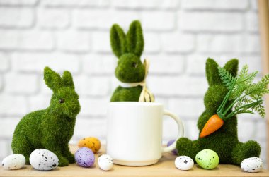 Dekoratif tavşanlar bahar şenlikleri için renkli yumurtaların arasında bir kupanın yanında otururlar..