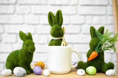 Paskalya yumurtaları ve beyaz kupayla yeşil tavşan figürleri bahar atmosferini oluşturur..