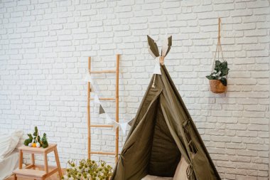 Dekoratif bitkiler ve mobilyalarla çevrili bir çadırın yer aldığı eğlenceli bir yer..