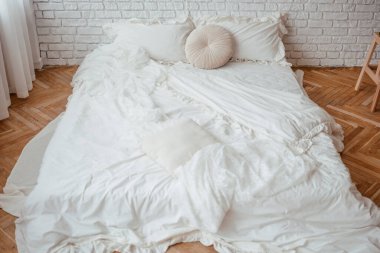 Yumuşak beyaz yatak odası, parlak bir yatak odasının ahşap zeminine saçılmış..