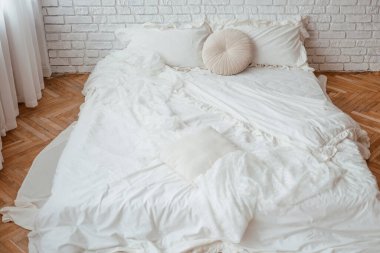 Yumuşak beyaz yatak ve yastıklar şık bir odada huzurlu bir atmosfer yaratır..