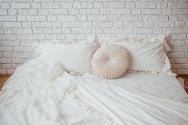 Yumuşak beyaz yatak ve yuvarlak yastıklı rahat minimalist yatak..