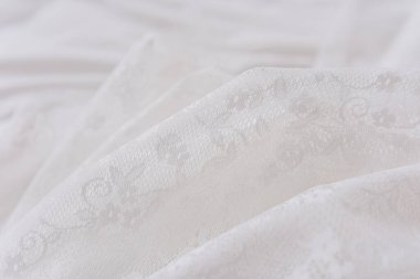 Zarif çiçek desenleri içeren yumuşak beyaz kumaş bir yüzeyde zarifçe yatıyor..