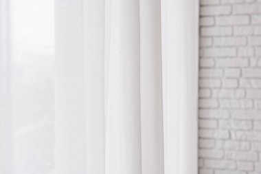 Işık perdelerin arasından süzülür gün ışığında dokulu tuğla bir duvardan sarkan.