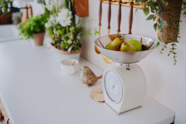 Taze armutlar yeşilliklerle dolu güneşli bir mutfakta dinleniyor..