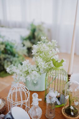 Bright white room features flowers in vases and decorative items on the table. clipart