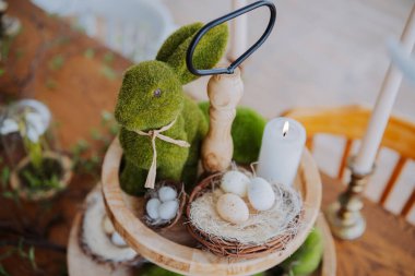 Paskalya düzeninde yosun kaplı bir tavşan, yumurta ve mum sergilenir..