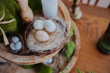 Dekoratif düzenleme, ahşap bir masanın üzerindeki bir yuvaya yerleştirilmiş çeşitli yumurtalar içerir..