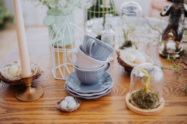 Bahar temalı dekorlar masaya istiflenmiş fincanlar, mumlar ve doğal elementler.