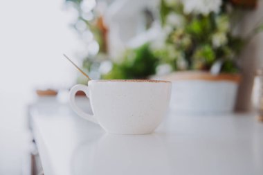 Yeşillik dolu parlak, davetkar bir masada sıcak bir fincan kahvenin tadını çıkarıyorum..