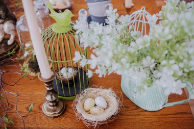 Dekoratif yumurtalar, çiçekler ve mumlarla süslenmiş bahar temalı bir dekor..