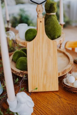 Bir ahşap kesme tahtası yeşil dekorun ve kırsal bir masada mumların arasında duruyor..