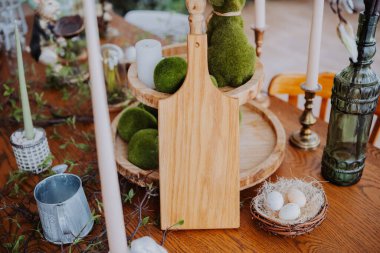 Bir bahar toplantısı için kırsal dekorasyonlarla süslenmiş bir yemek masasında yosun topları yer alır..