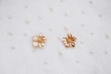 Yumuşak beyaz bir zemine yerleştirilmiş incili iki altın çiçek..