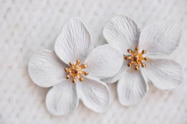Altın erkekli iki zarif beyaz çiçek yumuşak, desenli bir yüzeyde oturur..