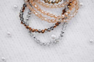 Ilık ve serin tonlarda parlak boncuklu bilezikler kumaşın üzerinde güzel durur..