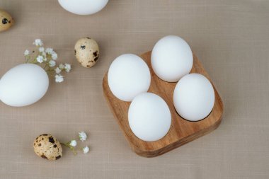 Tahta tepside beyaz yumurta ve bıldırcın yumurtası.