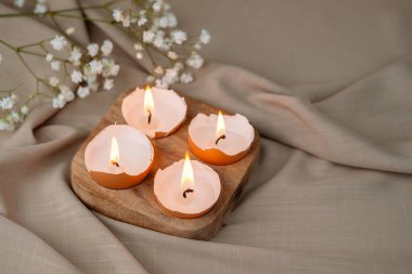 Eggshell burning candles with flowers. Easter background.  clipart