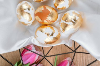 Pembe laleli sepetteki altın Paskalya yumurtaları, üst manzara. Paskalya kuşağı.