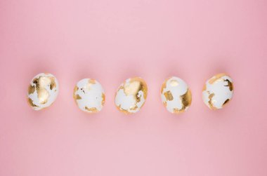 Pastel pembe arka planda Paskalya altın yumurtaları.