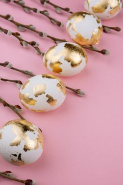 Pembe arka planda söğüt dalları olan Paskalya altın yumurtaları. Paskalya arkaplanı.