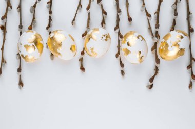 Beyaz arka planda söğüt dalları olan Paskalya altın yumurtaları. Paskalya arkaplanı. Mesaj için uygun bir yer..