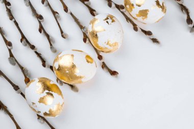 Beyaz arka planda söğüt dalları olan Paskalya altın yumurtaları. Paskalya arkaplanı.