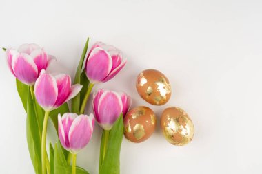 Beyaz arka planda laleleri olan altın sarısı yumurtalar, üst manzara. Paskalya bayrağı. 