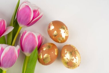 Beyaz arka planda laleleri olan altın sarısı yumurtalar, üst manzara. Paskalya bayrağı. 