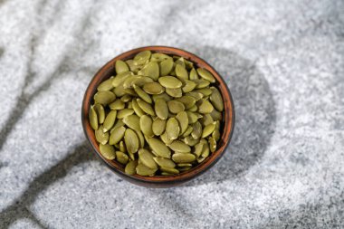 Bir kase yeşil kabak çekirdeği dokulu taş zemin üzerinde