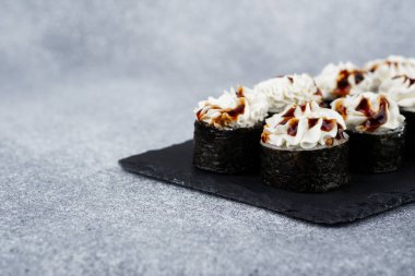 Kremalı krema ve serpilmiş sosla kaplı lezzetli suşi ruloları..