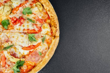 Üzerine peynir, domates ve siyah arka planda otlar konmuş taze pişmiş pizza..