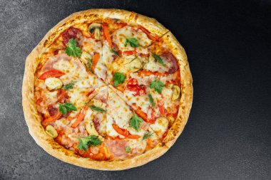 Taze pişmiş bir pizzada canlı sebze ve et parçaları yer alır..