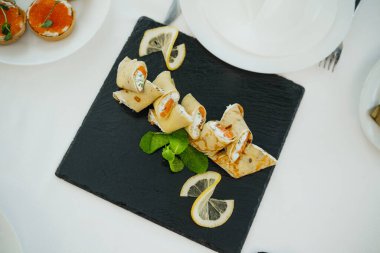 Limon dilimleriyle süslenmiş somon ve krem peynirle dolu tuzlu krepler..