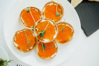 Portakallı havyar ve kremalı aperatifler bir tabağa güzelce yerleştirilmiş..