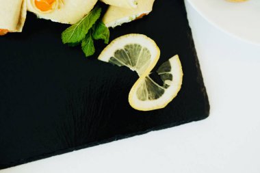 Limon dilimli rulo yiyeceklerle dolu canlı bir tabak tahtaya oturur..