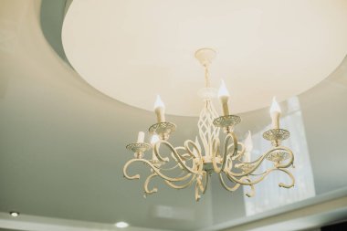 Dekoratif bir avize şık bir tavandan sarkıyor, odaya cazibe katıyor..