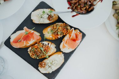 Çeşitli gurme aperatifleri bir toplantıda siyah servis panosunda düzenlenir..