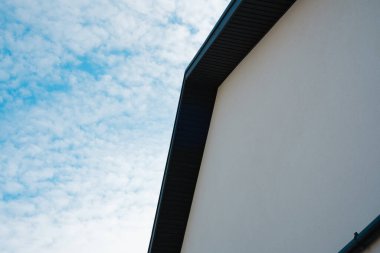 Mimari yapı, bulutlarla dolu parlak bir gökyüzünün köşesini gösteriyor..