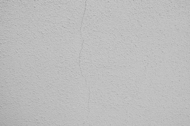 Çatlakları ve pürüzlü dokuyu gösteren beyaz beton bir duvarın yakın plan görüntüsü.