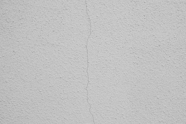 Beyaz bir duvar belirgin bir çatlak gösteriyor. Yüzeydeki eşitsizliği vurguluyor..
