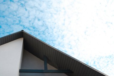 Güneş ışınları, bulutlu, uçsuz bucaksız mavi gökyüzünün altında bir evi aydınlatıyor..