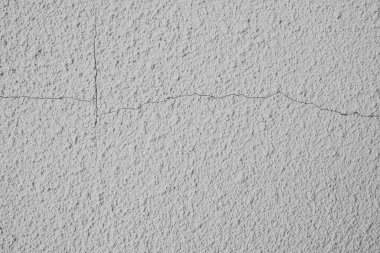 Kalıplı beyaz bir duvar belirgin bir çatlak içerir, yapısal aşınmayı vurgular.