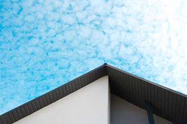 Eşsiz bulut desenleri çağdaş bir çatı çizgisinin üstündeki mavi gökyüzünü dolduruyor..