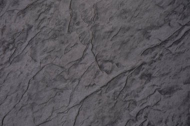 Gri taştan bir yüzeyin yakın plan görüntüsü eşsiz doku ve desenler sergiliyor..
