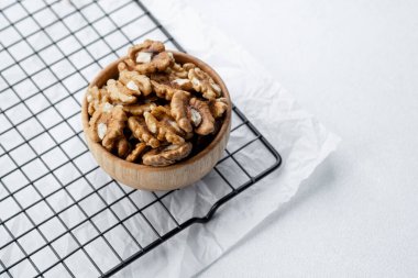 Cevizler ahşap bir kasede serinletici bir rafta beyaz bir arka fona karşı duruyor..