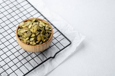 Taze kavrulmuş balkabağı tohumları, tel askıdaki ahşap bir kasede sergileniyor..